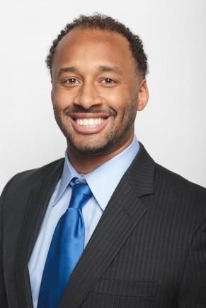 A man in a suit and tie is smiling for the camera