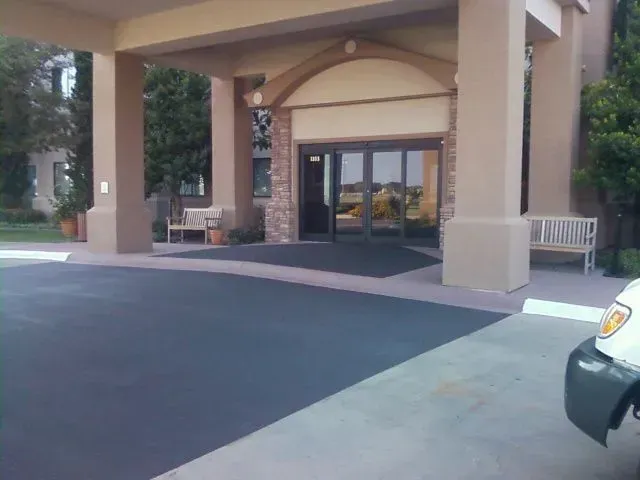 A white van is parked in front of a large building