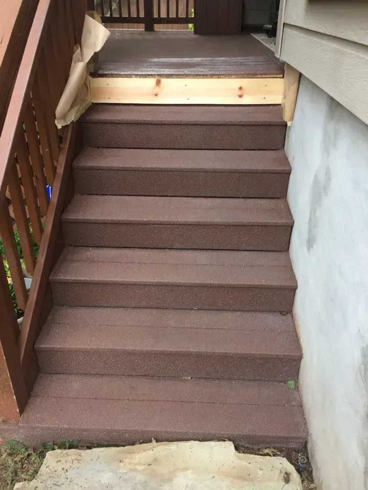 A set of stairs leading up to a house with a wooden railing.