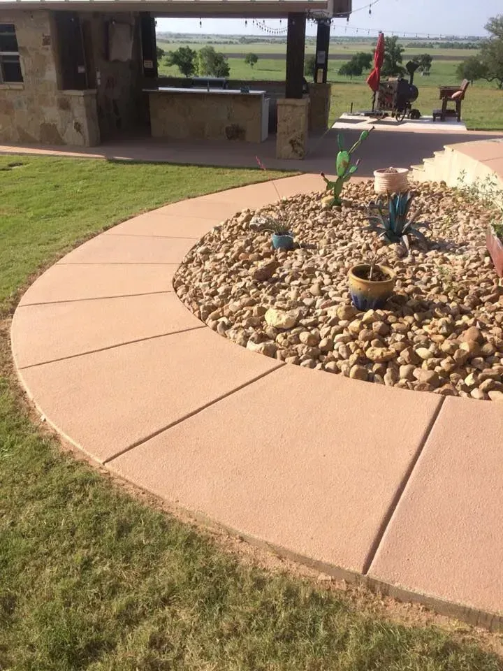 A concrete walkway surrounded by rocks and plants in a yard.