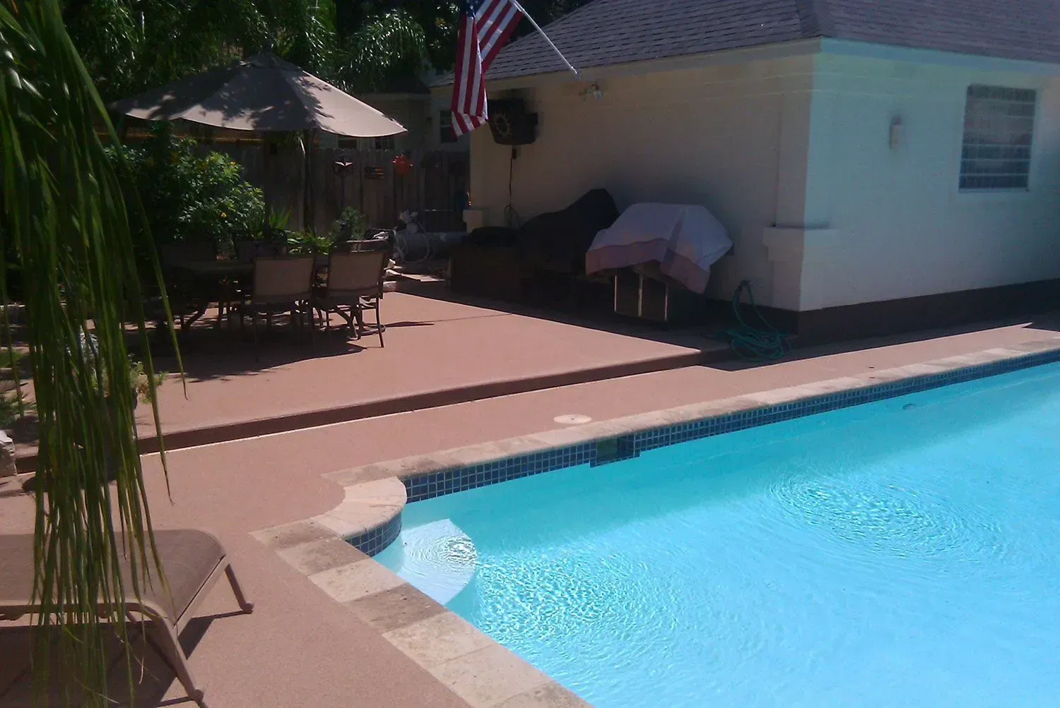 A large swimming pool with a house in the background