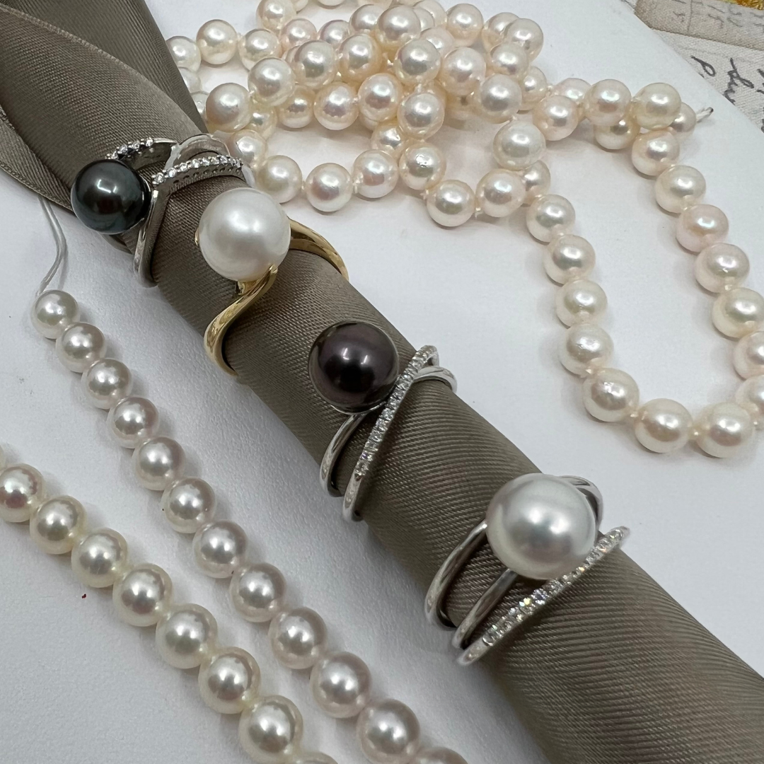 Pearl rings and necklaces on a gray fabric, showcasing elegant jewelry.