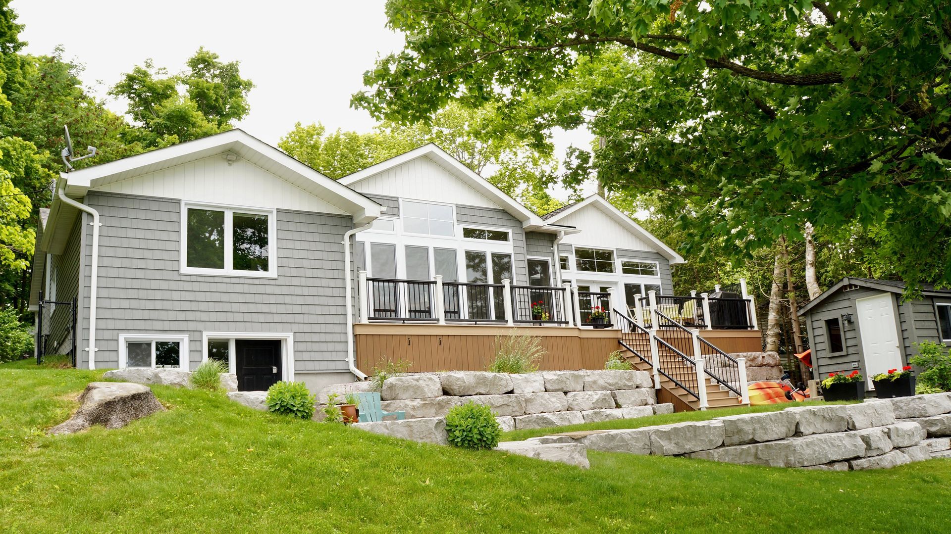 A large house with a lot of windows is sitting on top of a lush green hill.