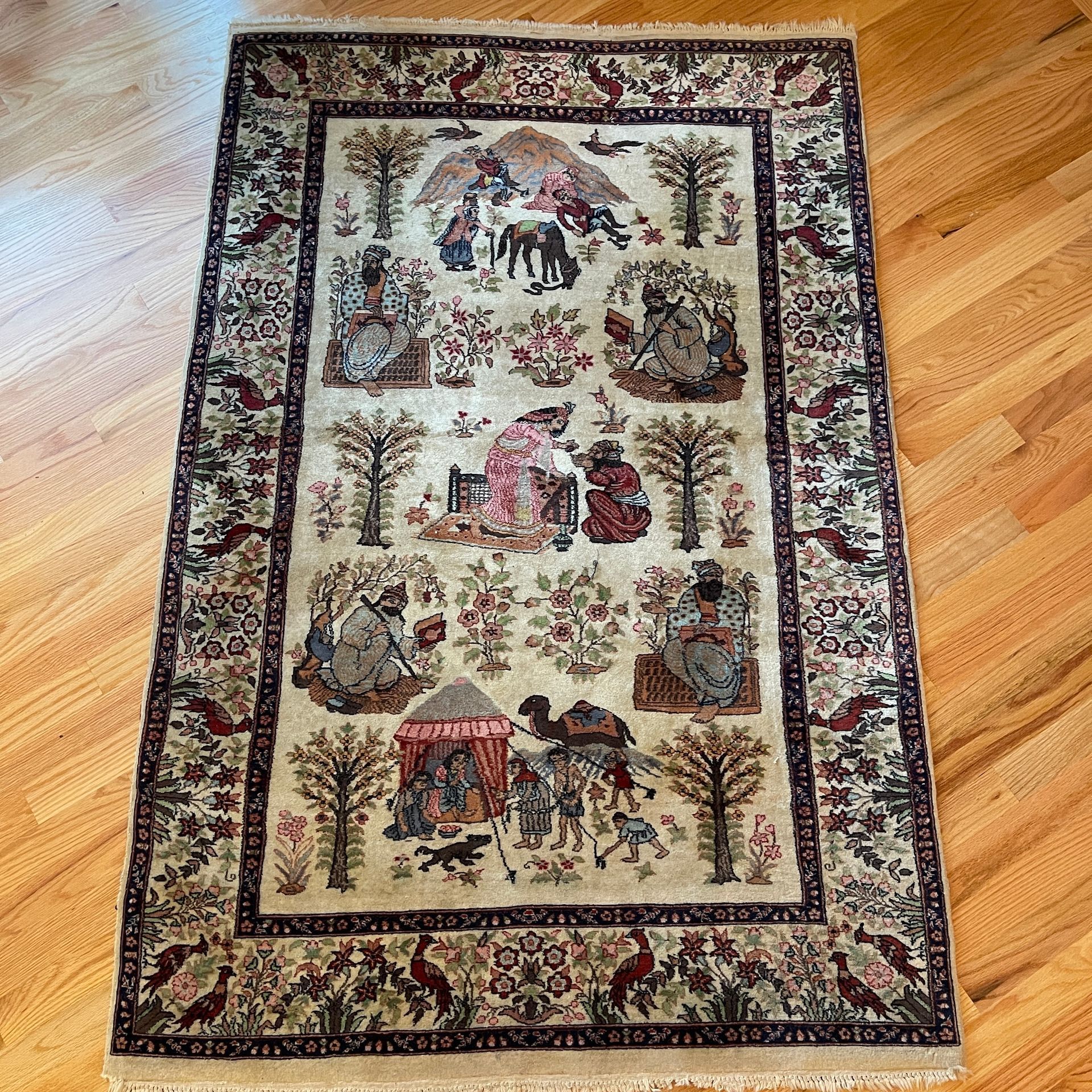Oriental rug with figures, trees, and animals in cream, red, and brown tones.