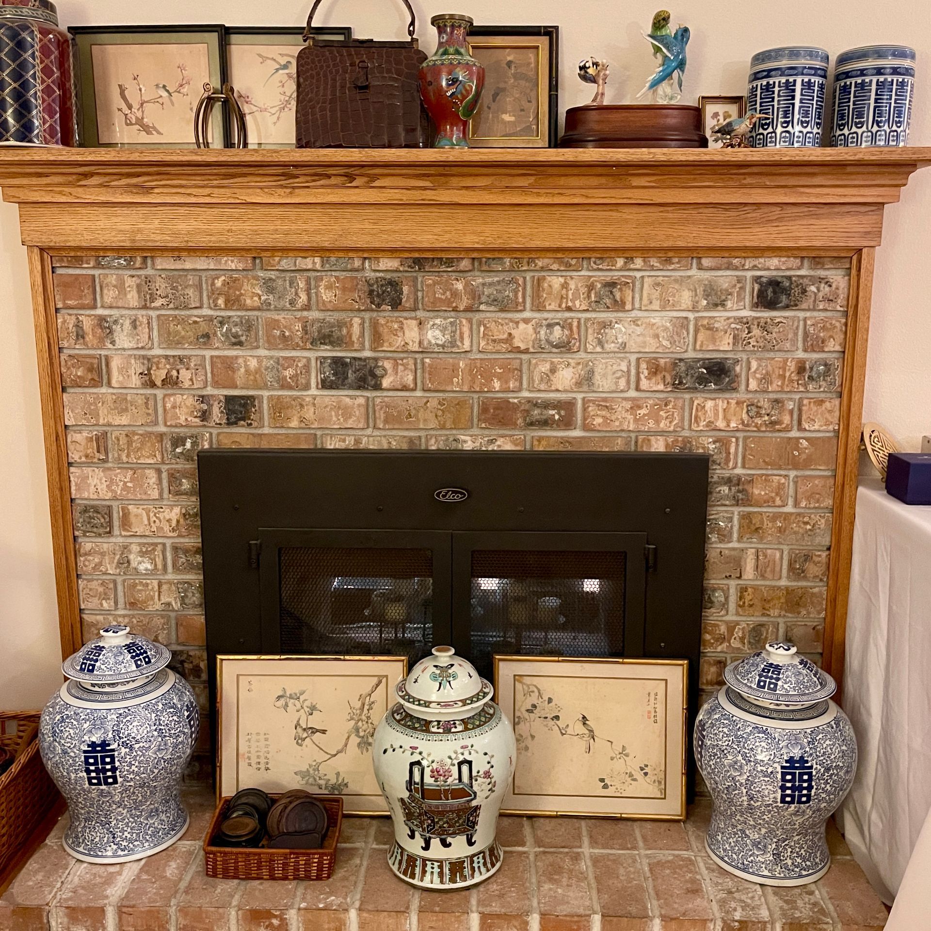 Fireplace with brick surround, wood mantel holding various decorative items, and blue and white jars.