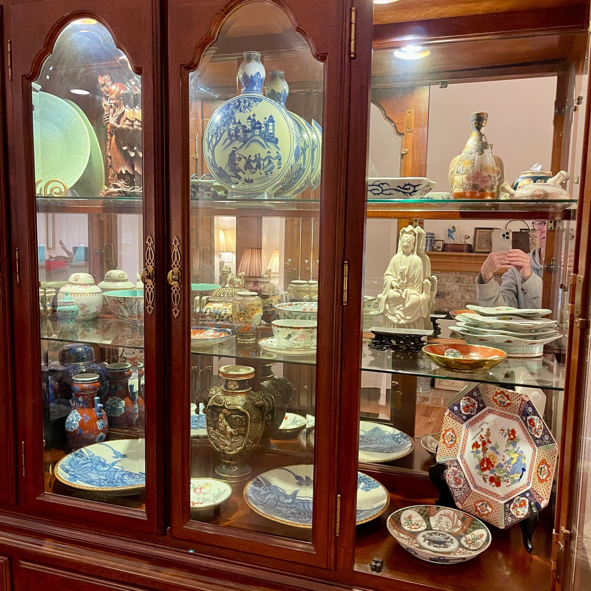 Wooden cabinet displaying various decorative china and figurines, including plates and vases.