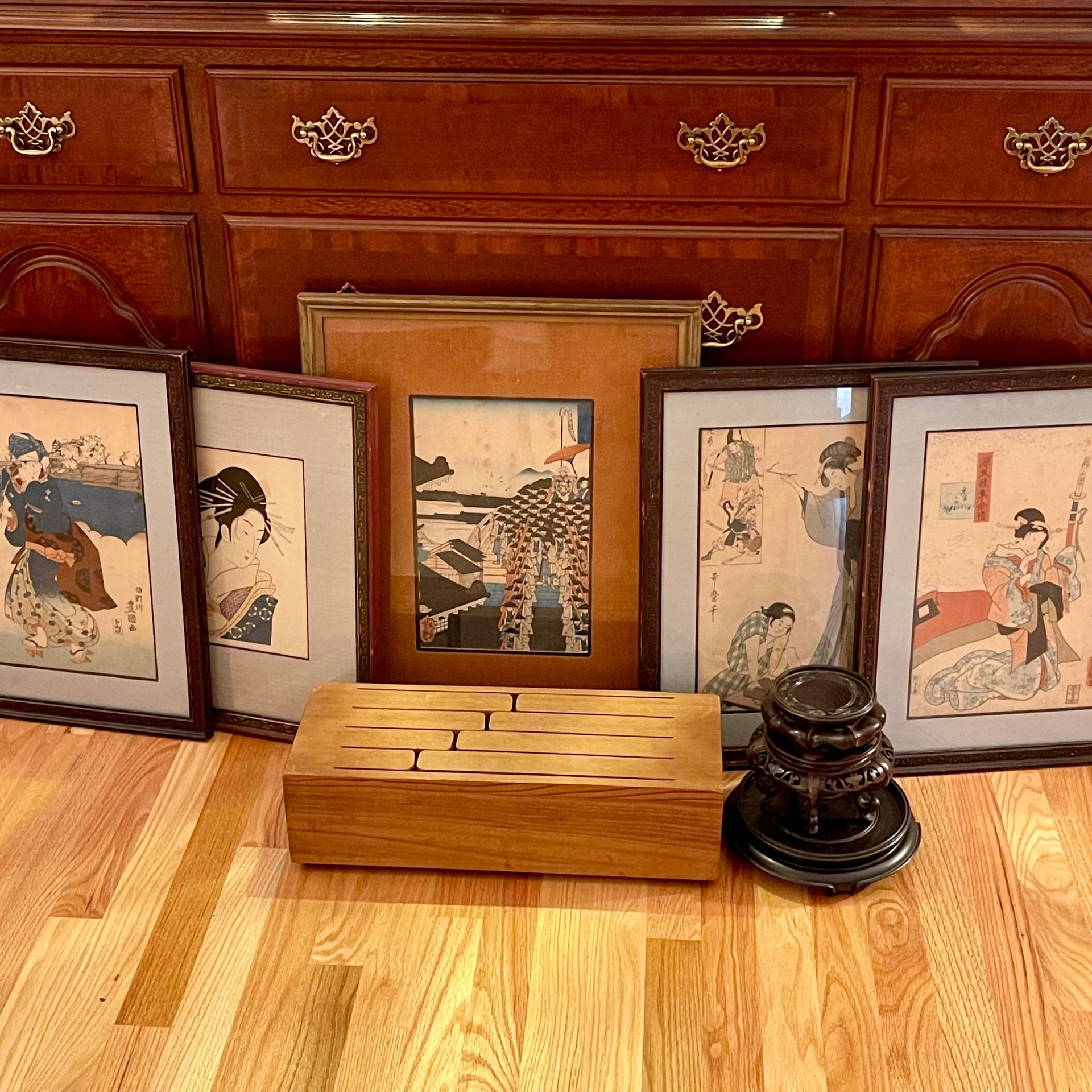 Japanese art prints, wooden box, and base on a wood floor in front of a dresser.