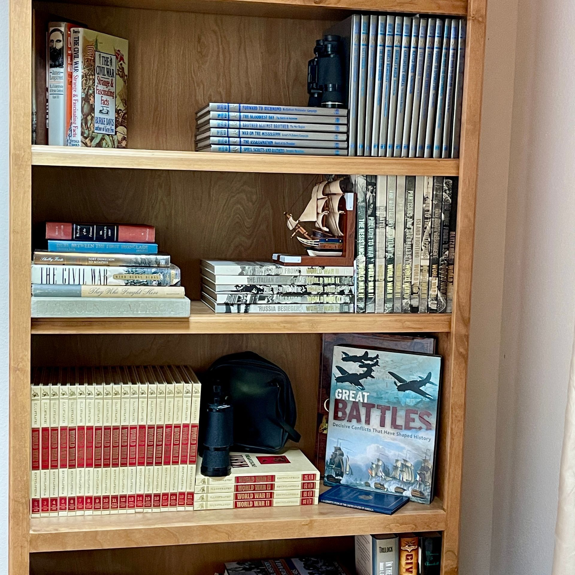 Wooden bookshelf with books, DVDs, binoculars, and other decorative items.