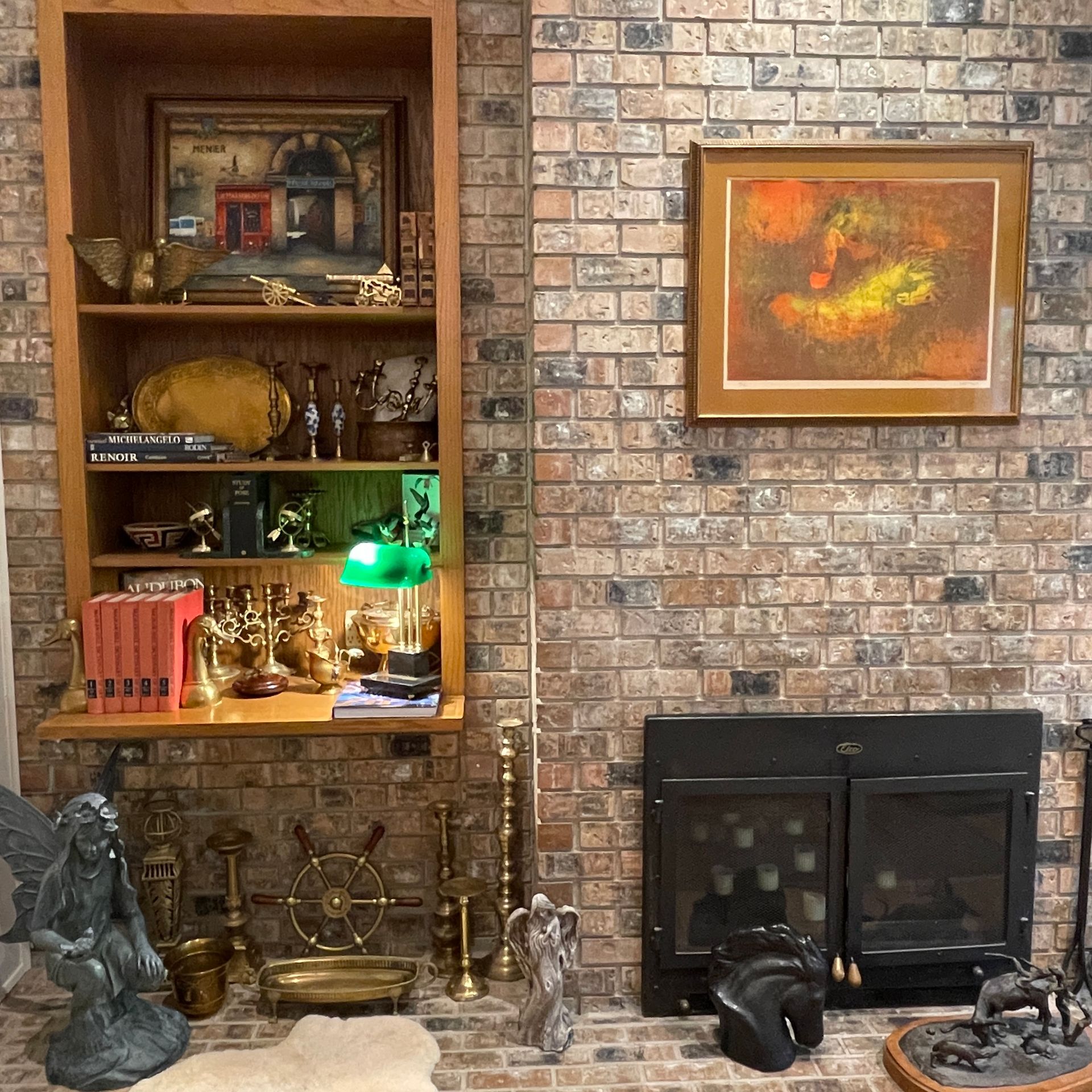 Brick wall with built-in bookshelf, fireplace, artwork, and decorative objects.