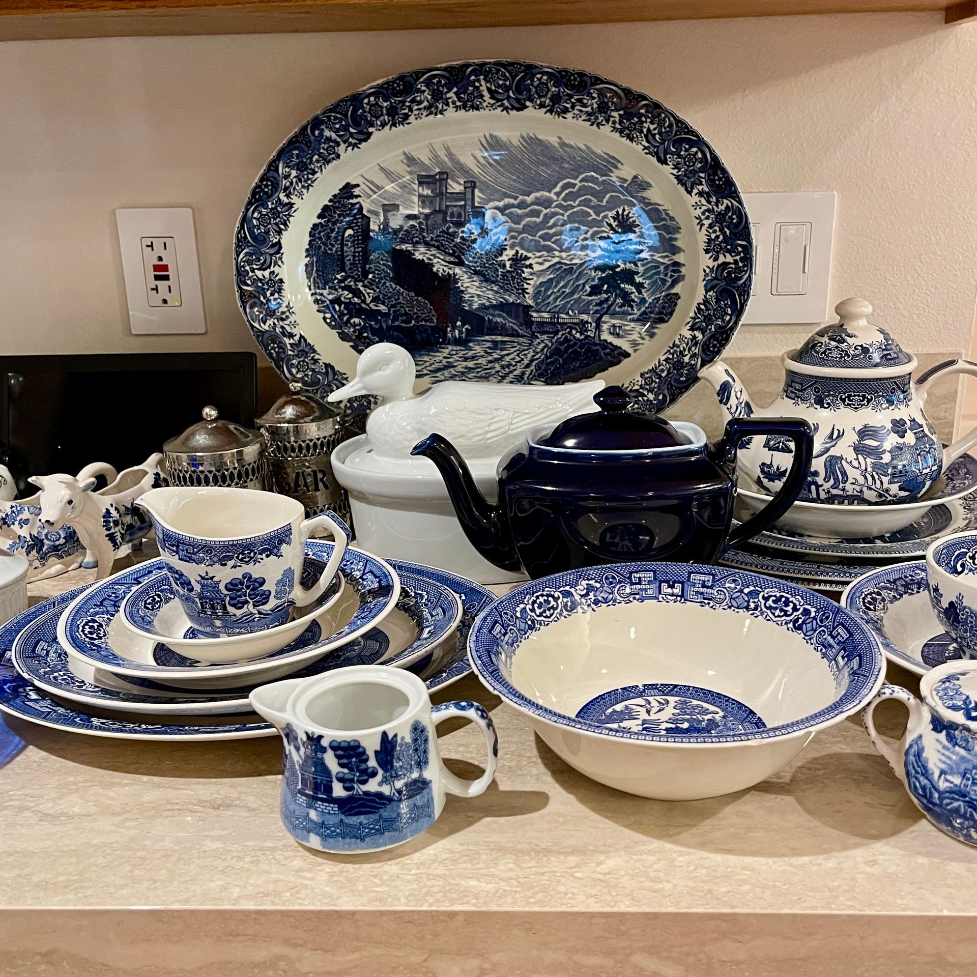 Blue and white dishware set on a countertop, including plates, bowls, and a teapot.