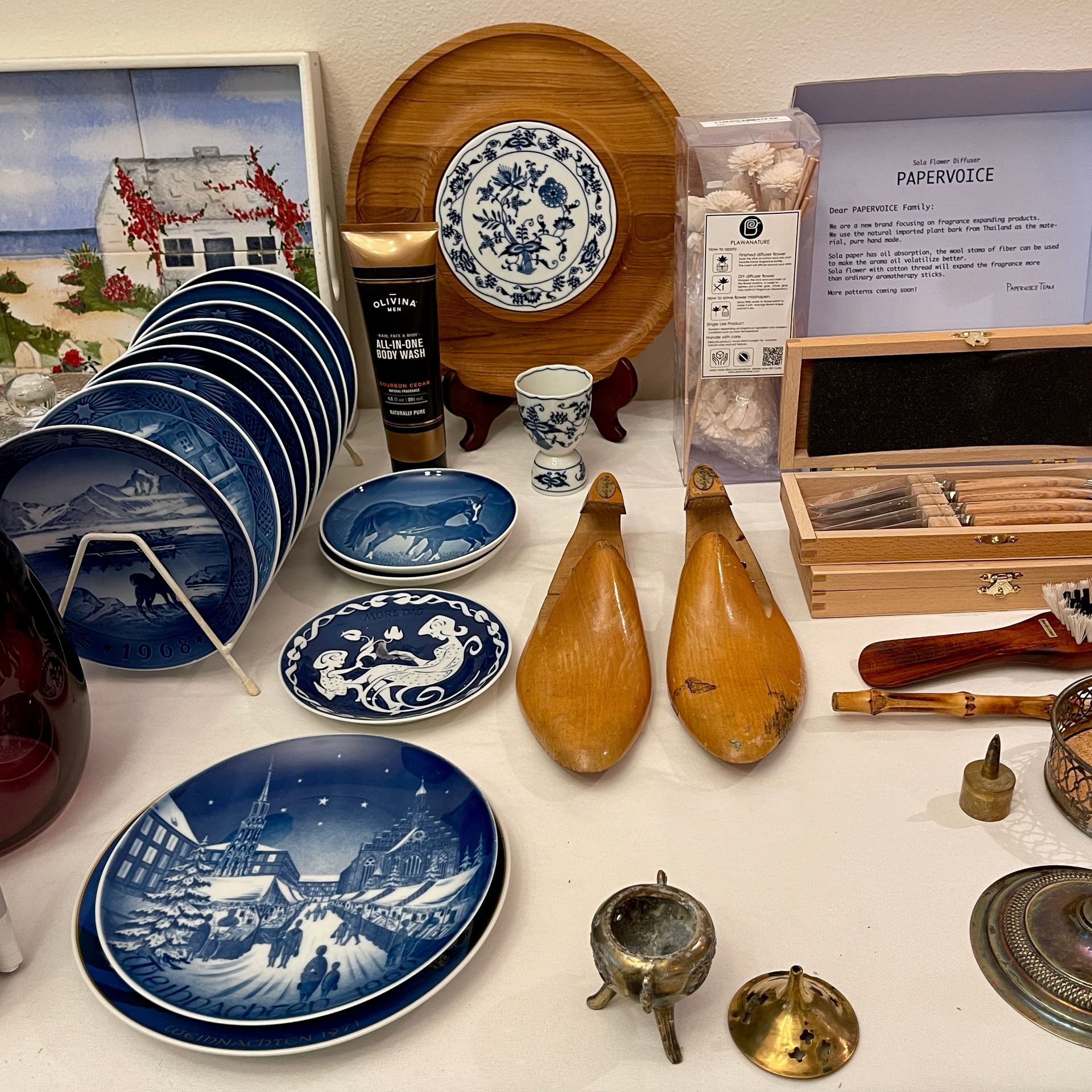 Assorted vintage plates, wooden items, and other decorative objects arranged on a white surface.