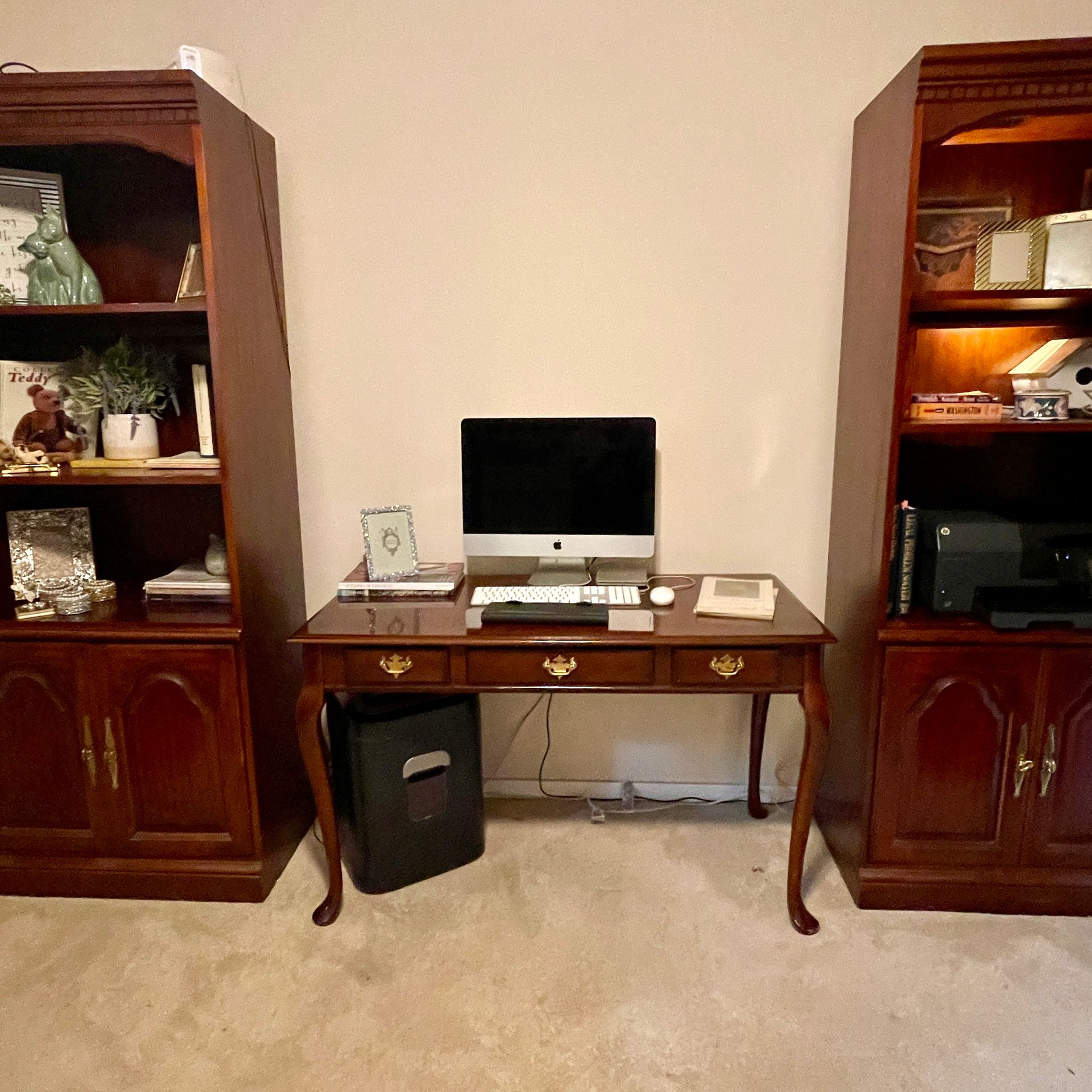 A home office with a desk between two dark wooden bookshelves; a computer sits on the desk.