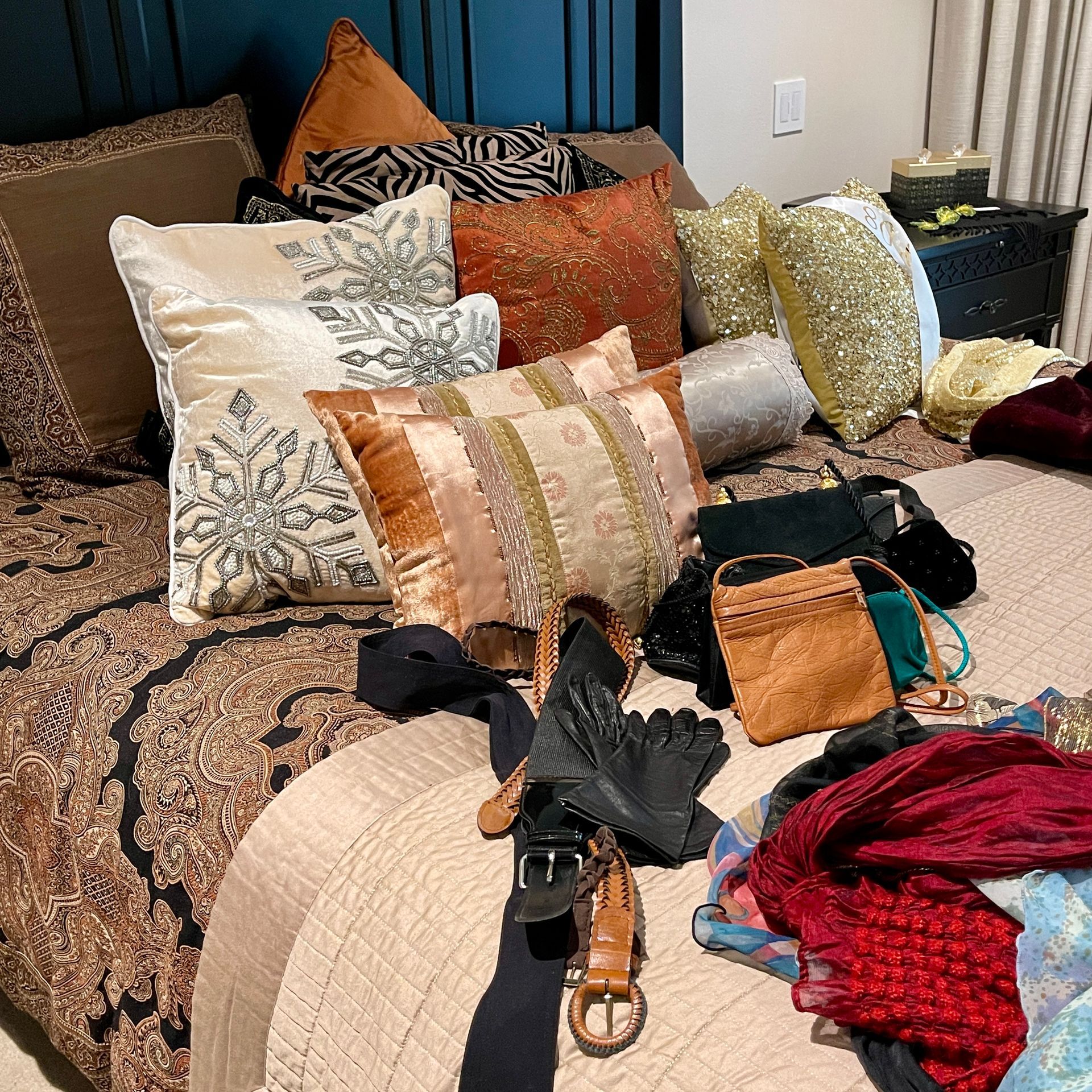 Bed with assorted pillows and a few purses, scarves, and accessories.