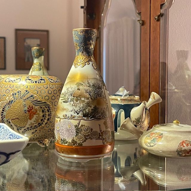 Japanese porcelain vase with landscape design in a glass cabinet.