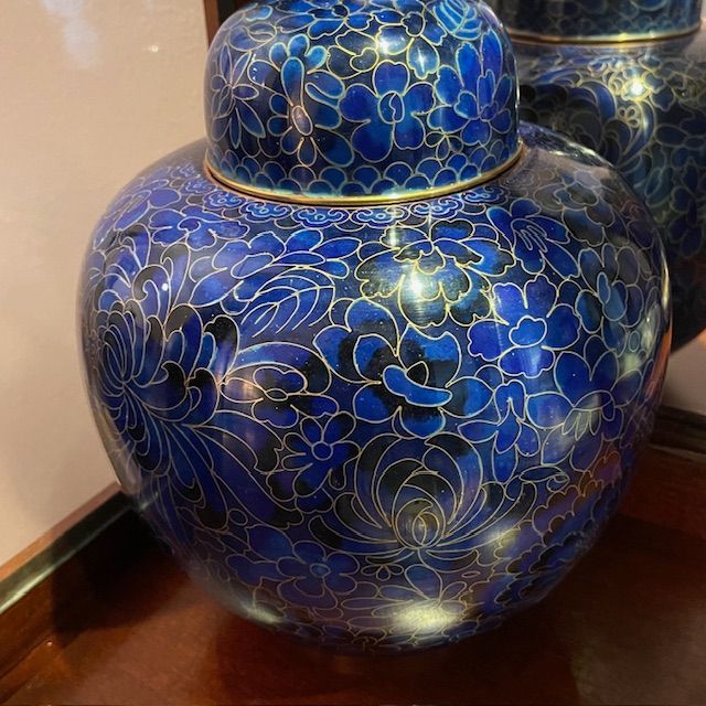 Blue and gold floral ginger jar with lid, set on a wooden surface, reflective background.