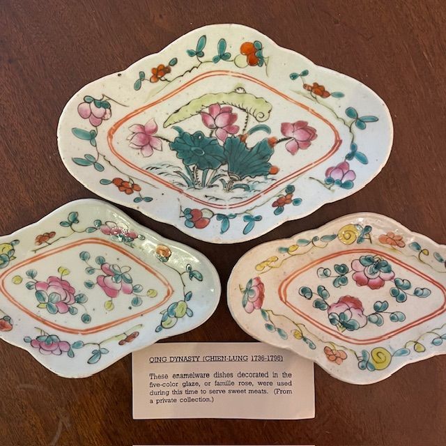 Three antique porcelain dishes with floral designs, a label below.