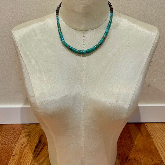 Turquoise beaded necklace on a mannequin torso, with brown and green beads.