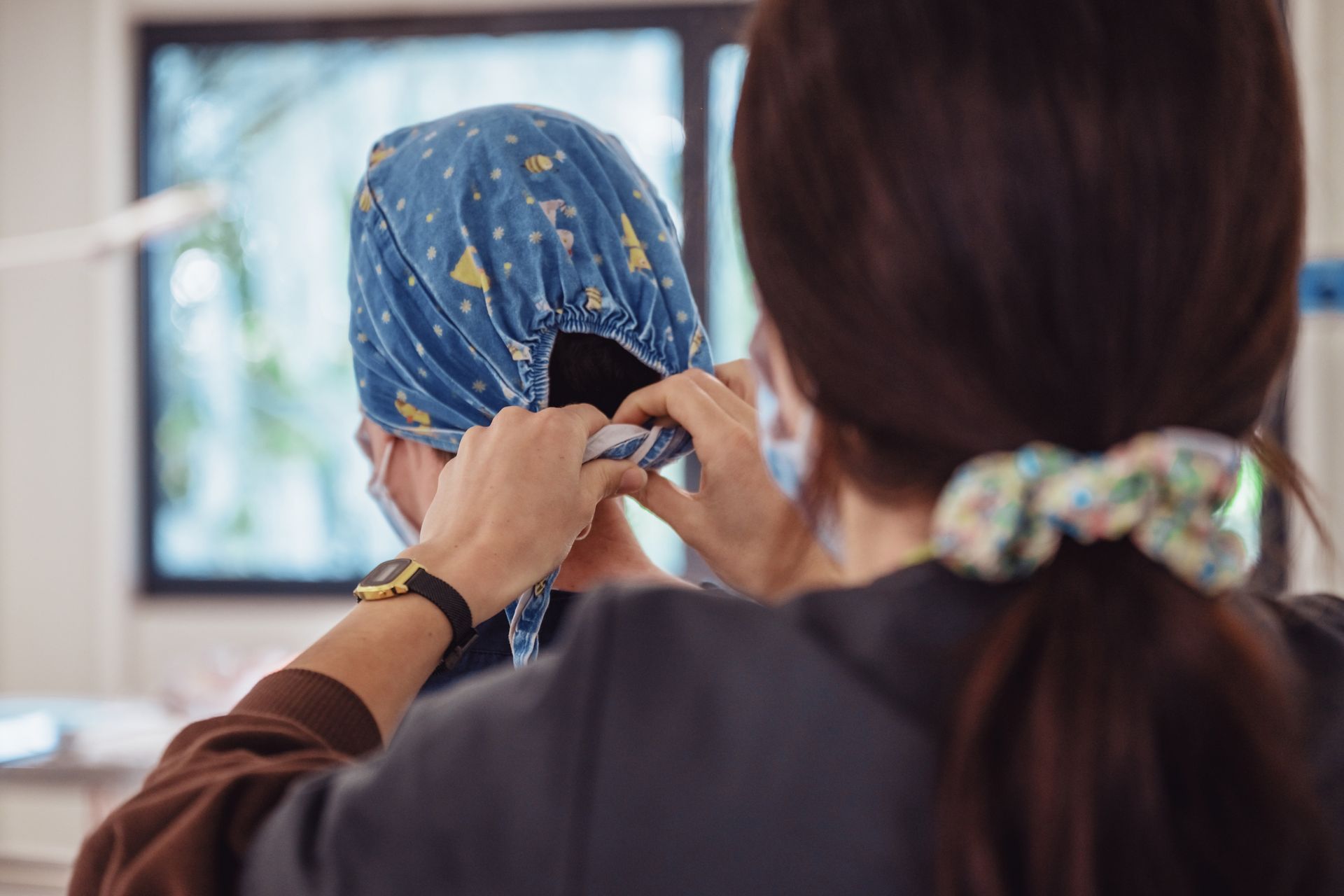 ASV ajuste une charlotte chirurgicale bleue à motifs sur une autre personne, à l'intérieur.