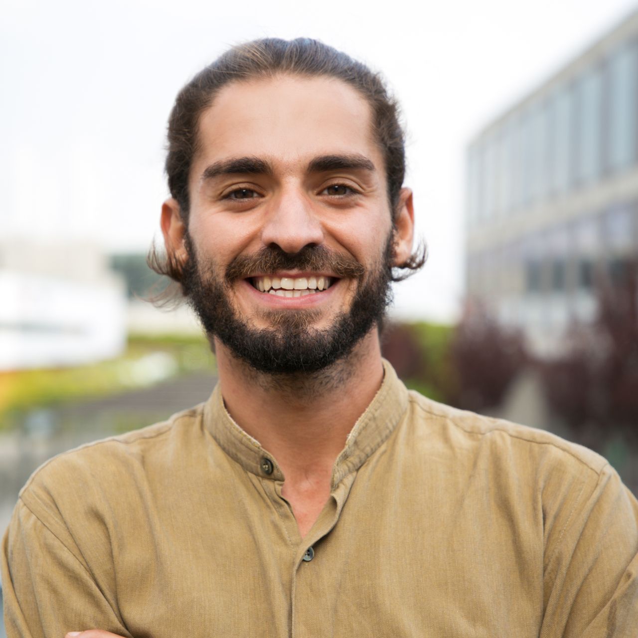 A man with a beard and long hair is smiling for the camera