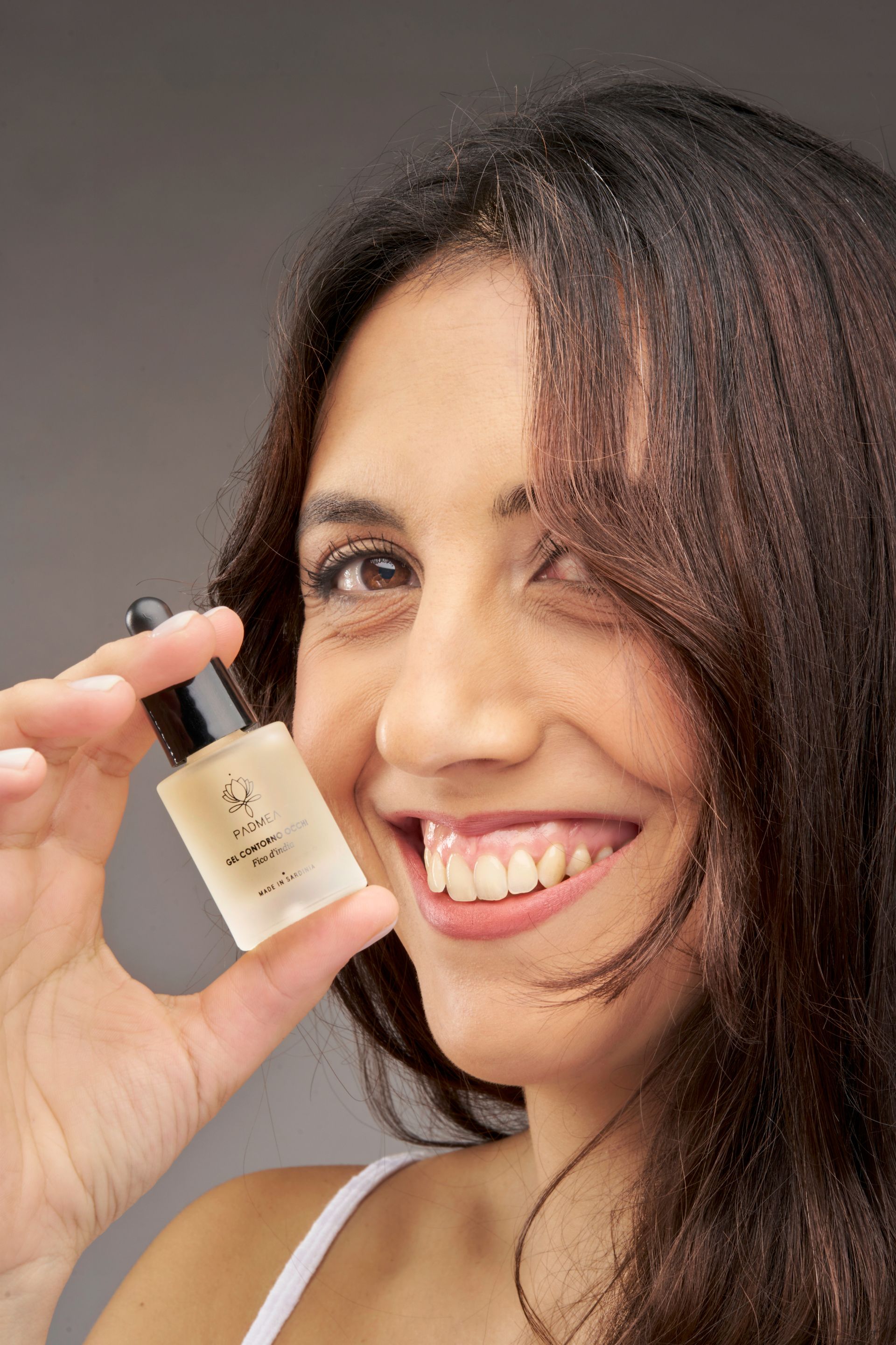 Una donna sorride mentre tiene in mano una piccola bottiglia di lozione.