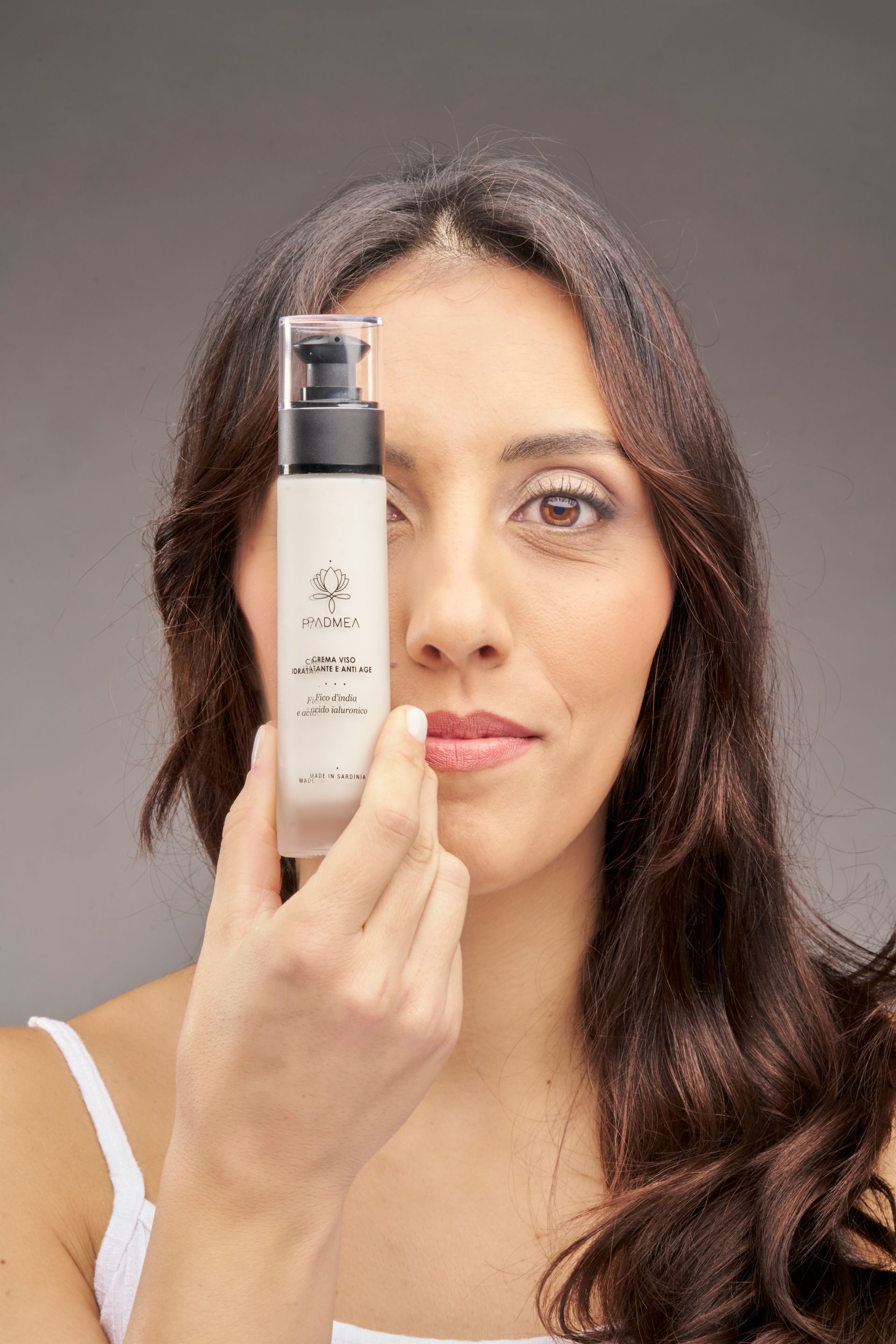 Una donna tiene una bottiglia di lozione davanti al viso.