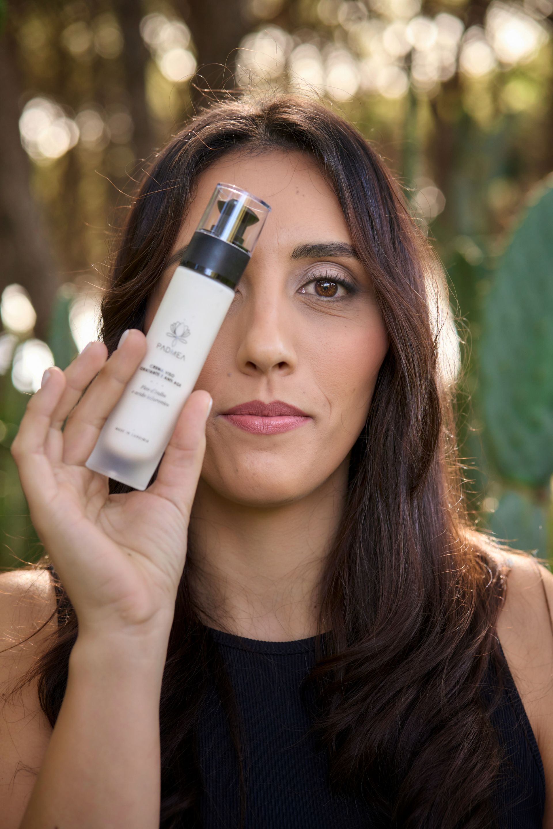 Una donna tiene una bottiglia di lozione davanti all'occhio.