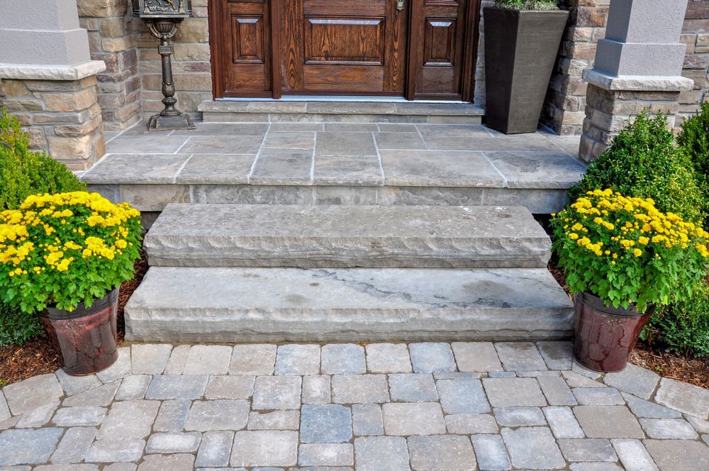 A stone porch with steps and potted plants in front of a house.