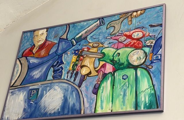 Dipinto di scooter colorati, tra cui blu, verde e rosso, con un uomo e una chiave inglese su sfondo blu.