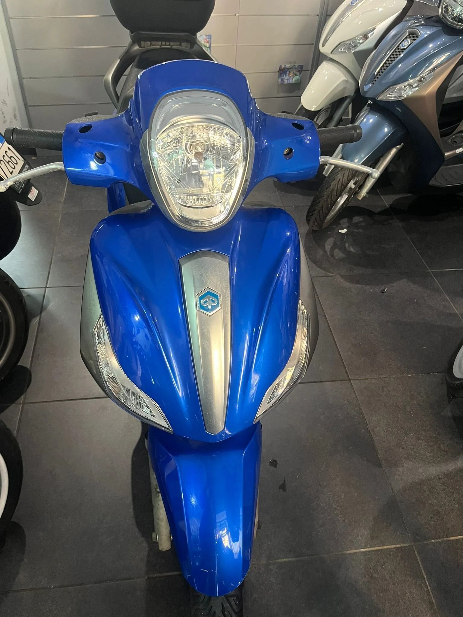 Scooter blu e argento parcheggiato al chiuso.
