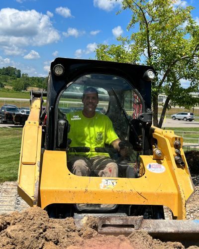 Zanesville Concrete Pros operator preparing ground with skid steer for concrete driveway and slab installation.