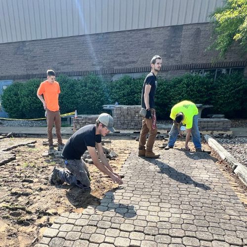 Concrete crew from Zanesville Concrete Pros removing old pavers to prepare for new stamped concrete patio installation.