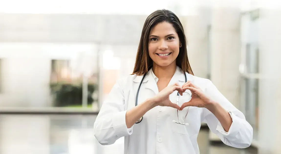A female doctor is making a heart shape with her hands.