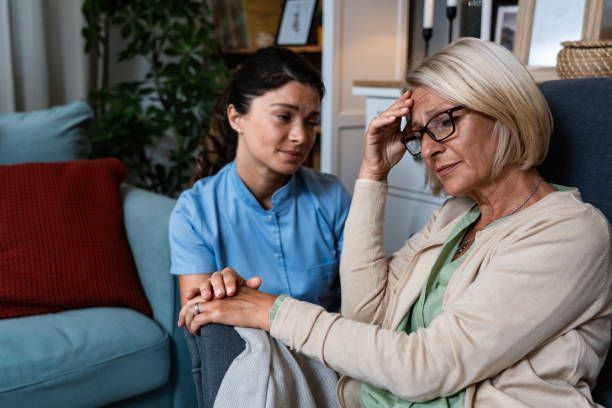 home health aide sits with a confused women at home with alzheimer's disease