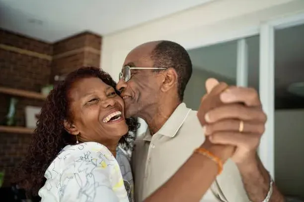 A man is kissing a woman on the cheek while they are dancing.