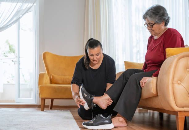 Home Health Aide observing elderly woman's legs for ulcers at home in New York