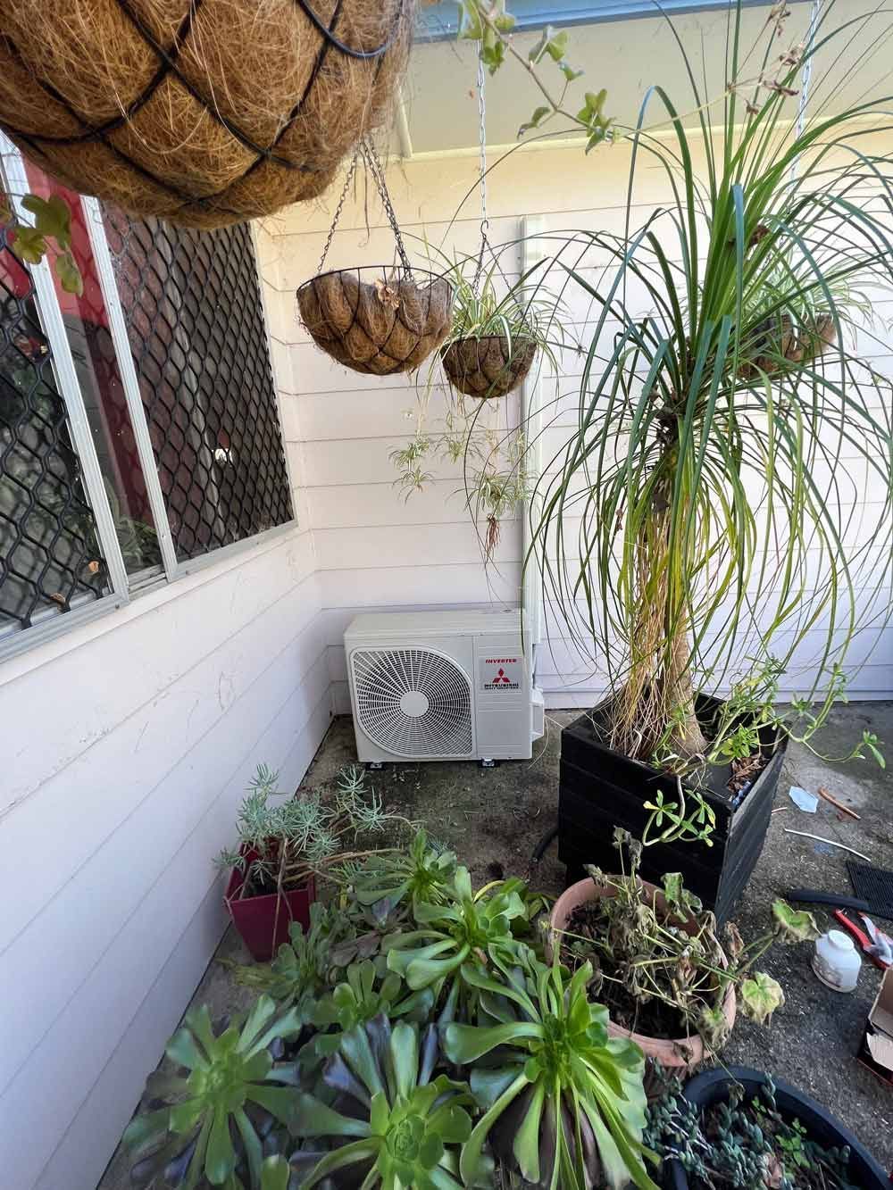 Outdoor Compressor in a Garden — Electrician in Port Macquarie, NSW