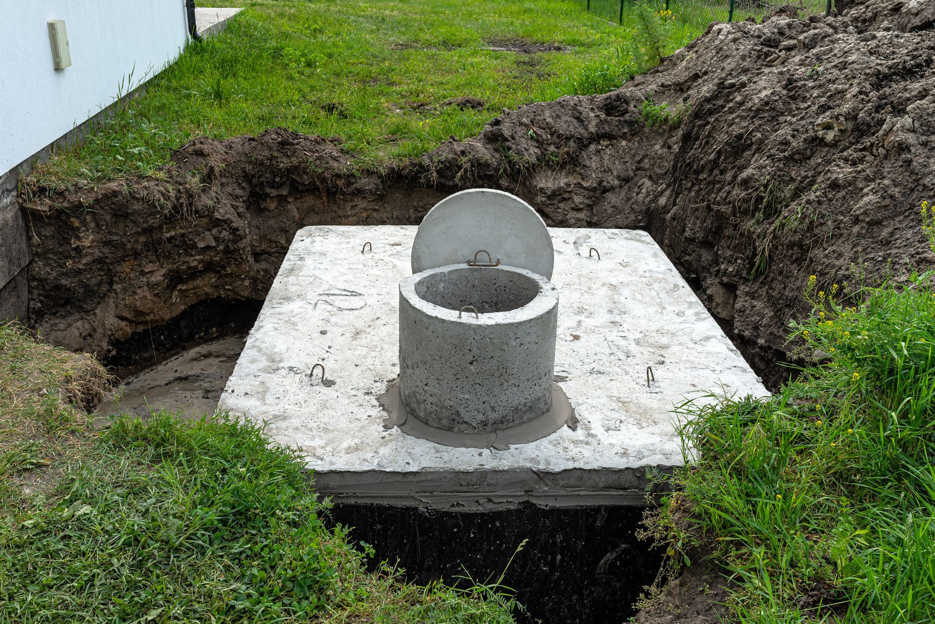 Exposed concrete septic tank in residential yard showing access lid during septic system inspection