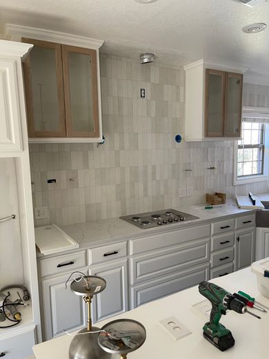 Kitchen with white cabinets, gas range, tiled backsplash, and wood-framed upper cabinets.
