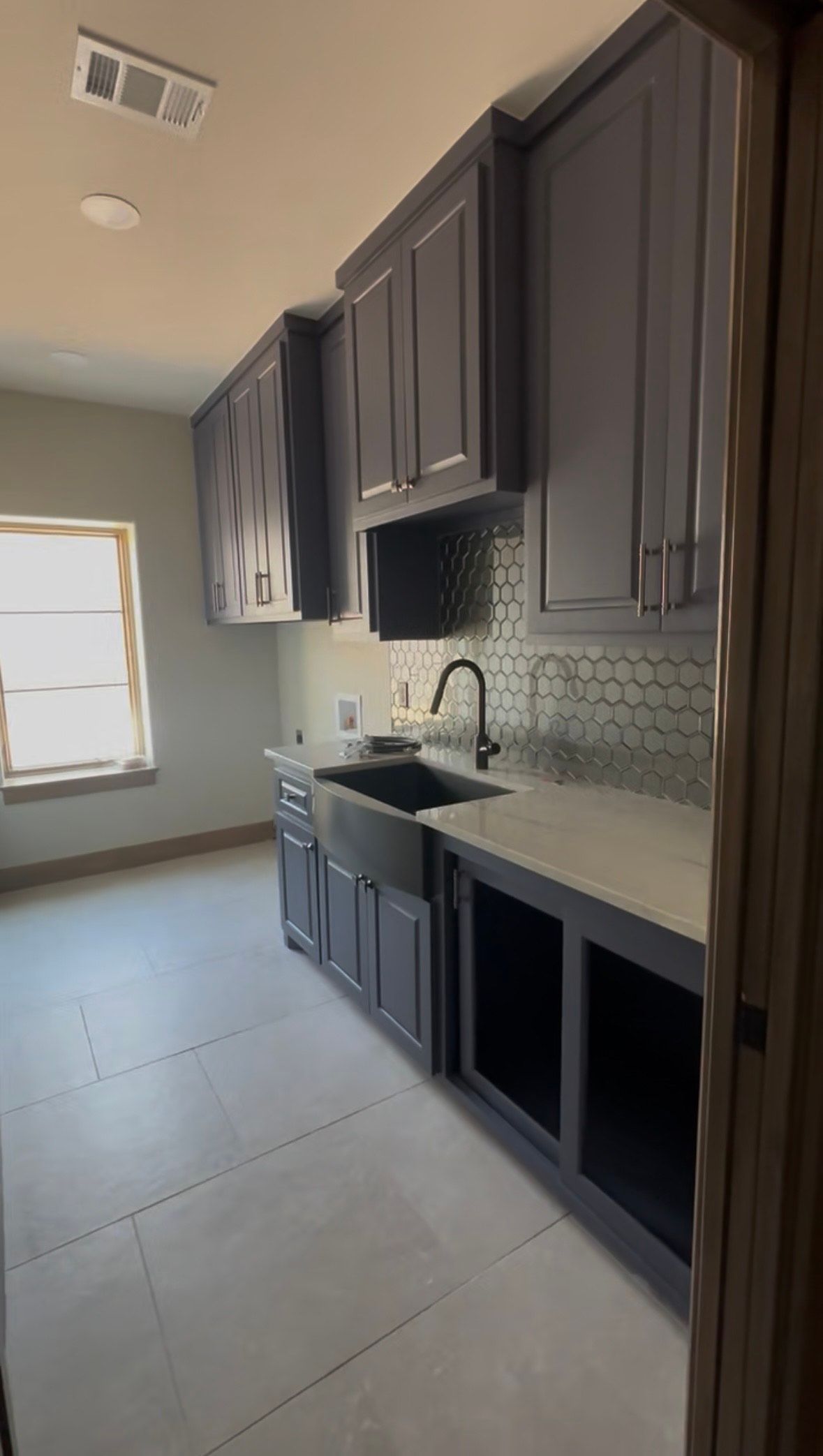 Laundry room with gray cabinets, a black sink, and a tiled backsplash.