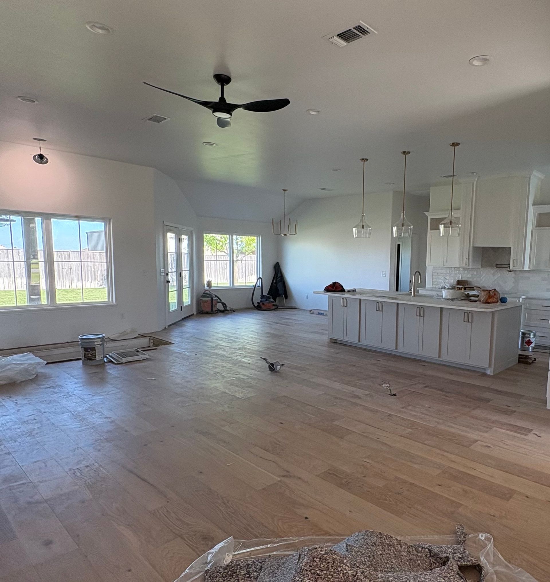 Interior of a spacious, empty room with light wood flooring and white walls, in progress of renovation.