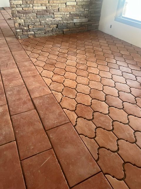 Brown, patterned tile floor with a brick accent, likely interior.