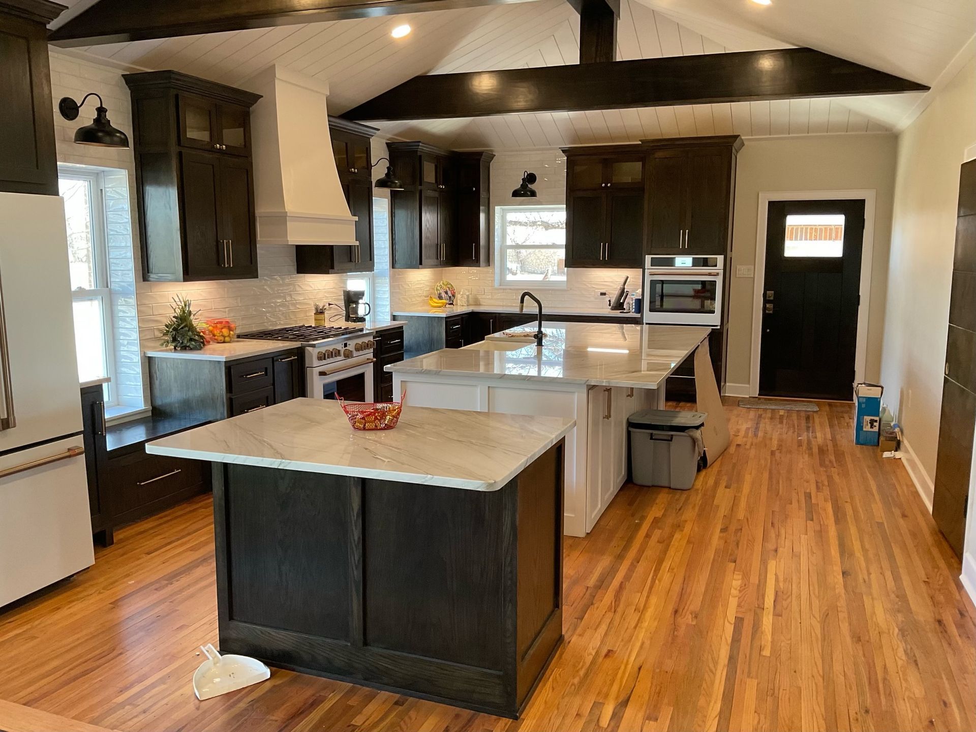 Modern kitchen with dark cabinetry, white countertops, wood floors, and island.