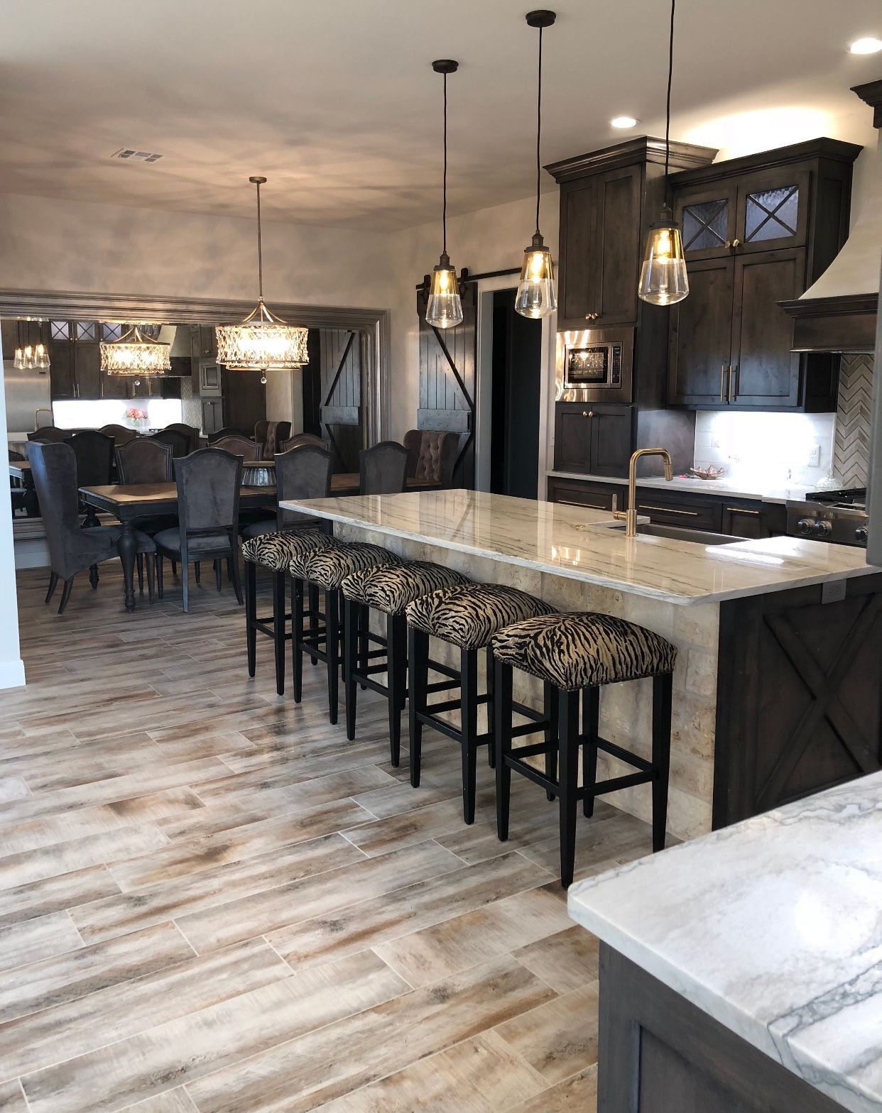 Kitchen with dark cabinets, large island with leopard print stools, and a dining area.