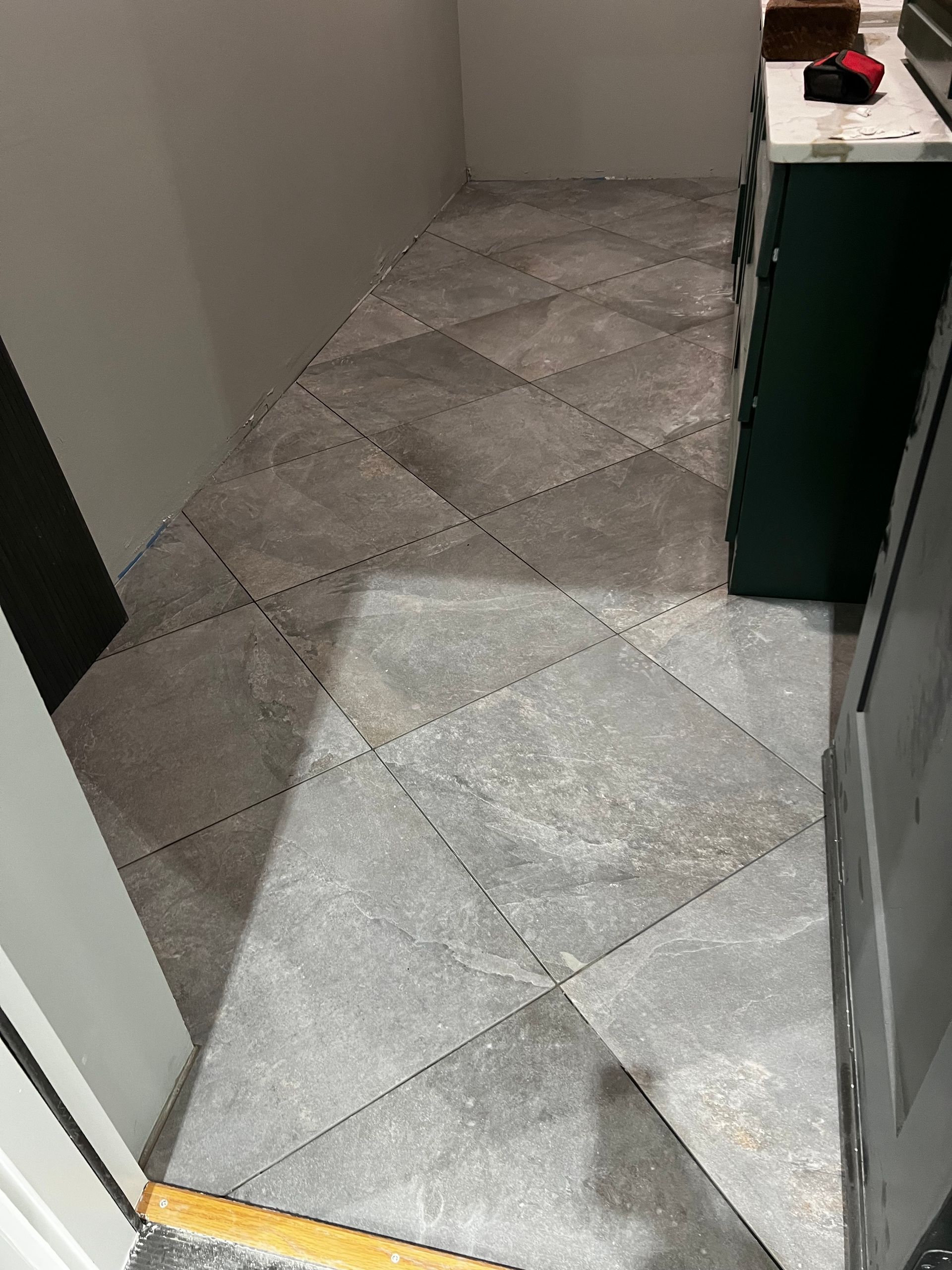 Gray tile flooring with a diamond pattern in a narrow hallway.