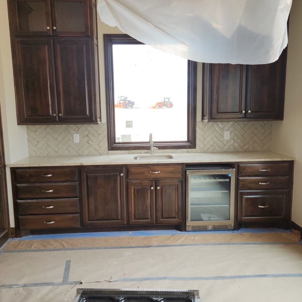 Dark wood kitchen cabinets with a window, countertop, and a built-in beverage cooler.