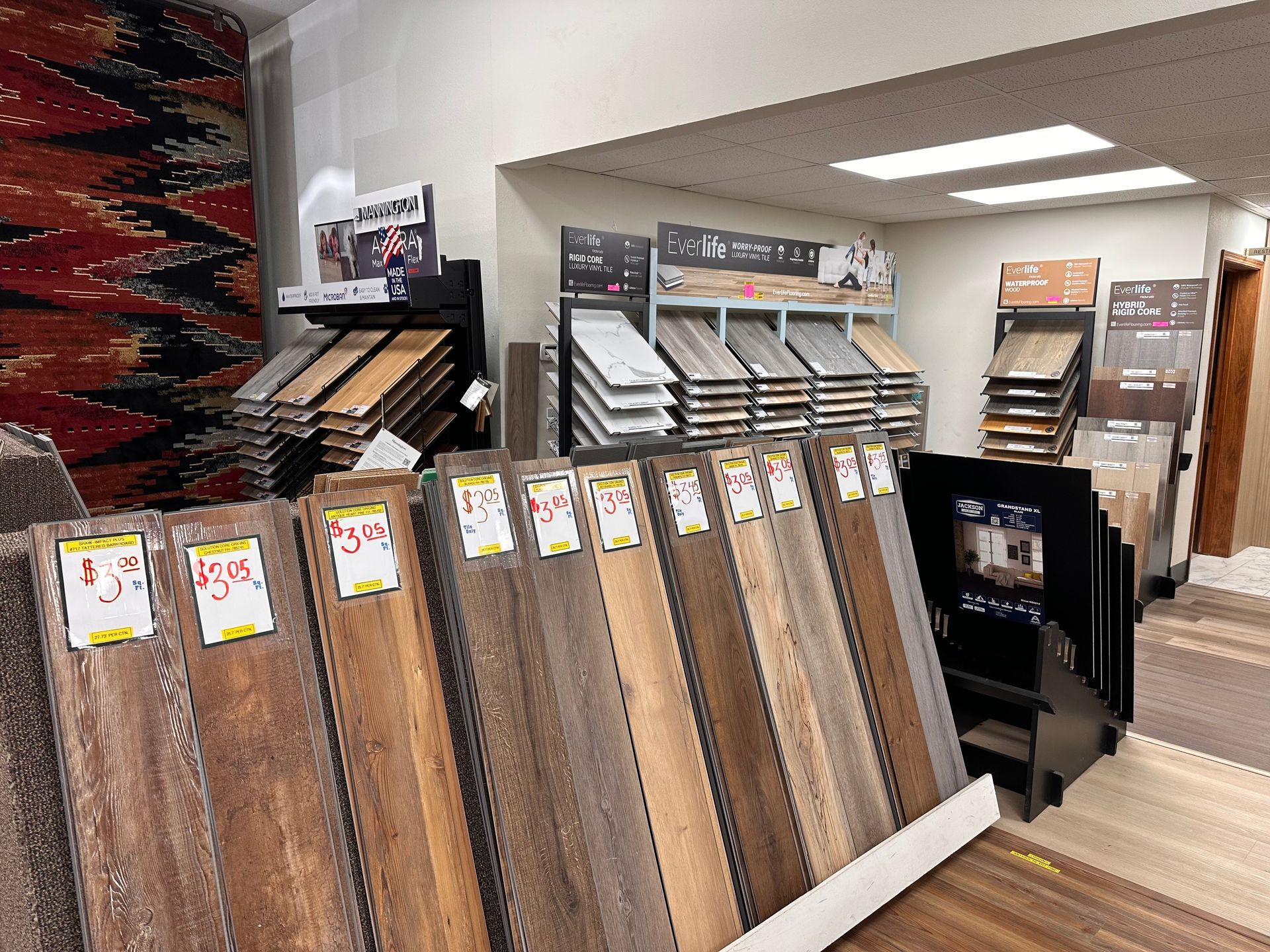 Flooring samples displayed in a showroom. Various wood-look planks with price tags. Flooring samples displayed in a showroom. Various wood-look planks with price tags.