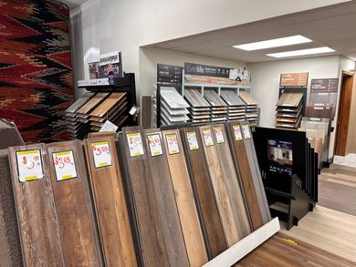 Flooring samples displayed in a showroom. Various wood-look planks with price tags.