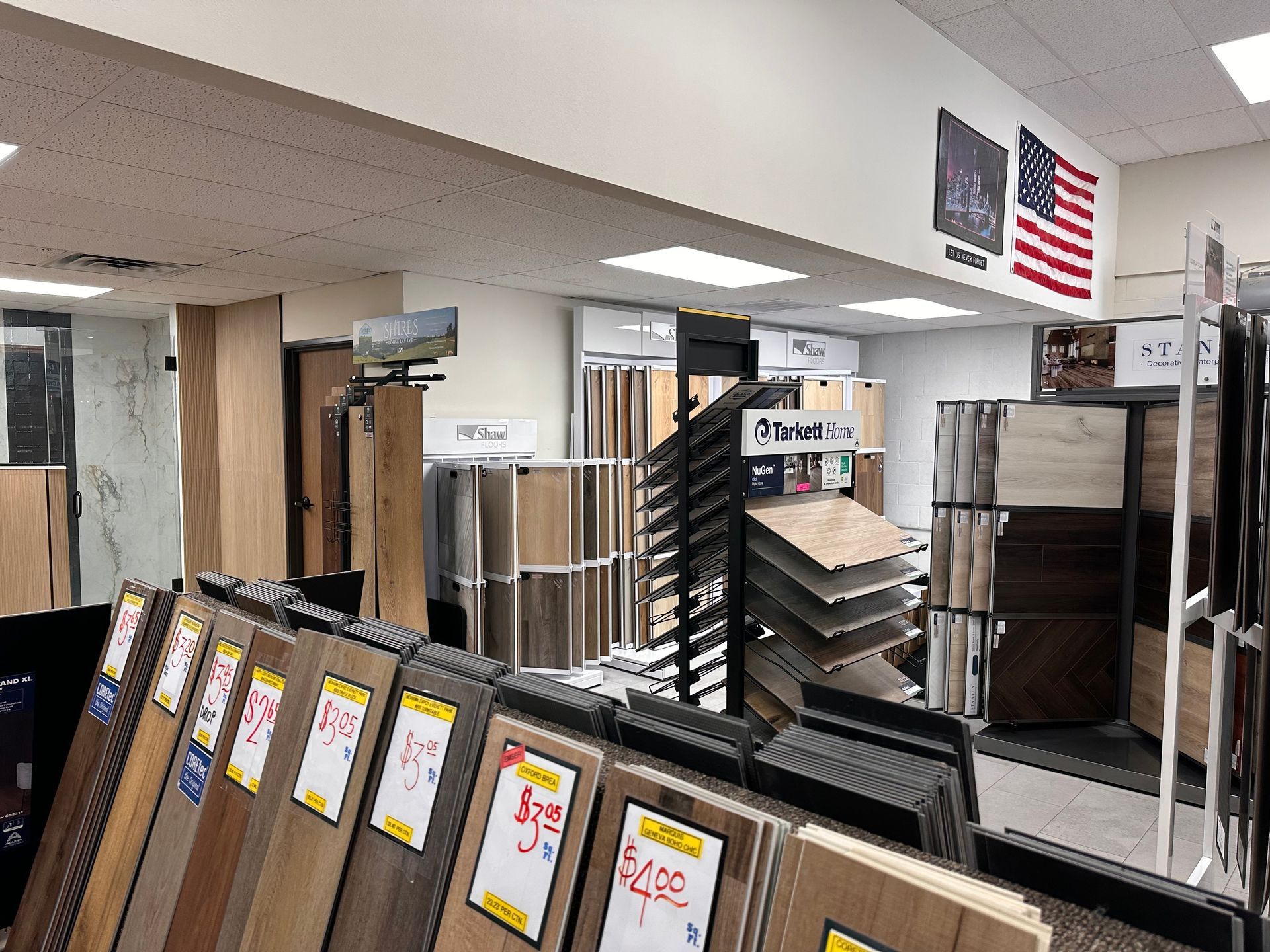 A flooring showroom displays samples of wood and tile flooring. American flag hangs on the wall. A flooring showroom displays samples of wood and tile flooring. American flag hangs on the wall.