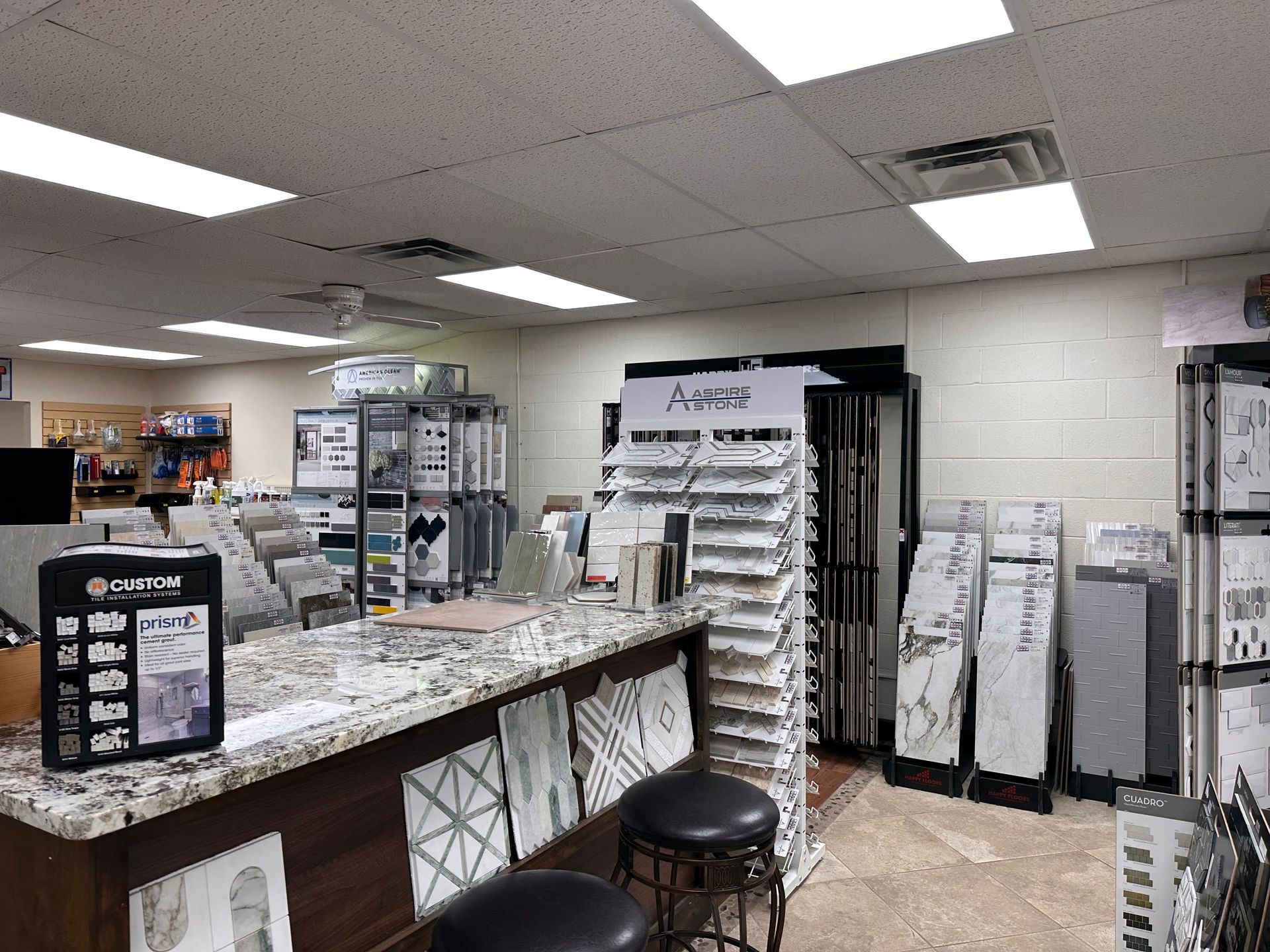 Tile showroom interior with displays, a counter, and stools. Tile showroom interior with displays, a counter, and stools.