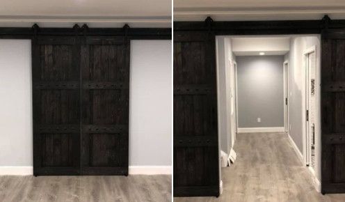 Two dark stained barn doors closed then open, revealing a hallway with gray walls and wood floors.